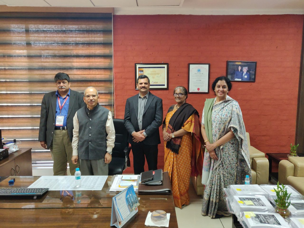 Five people stand together behind a desk in an office