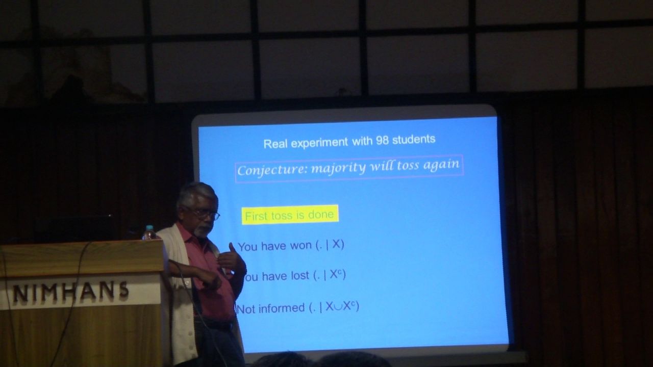Prof. Sisir Roy gestures beside a slide on a decision experiment with 98 students